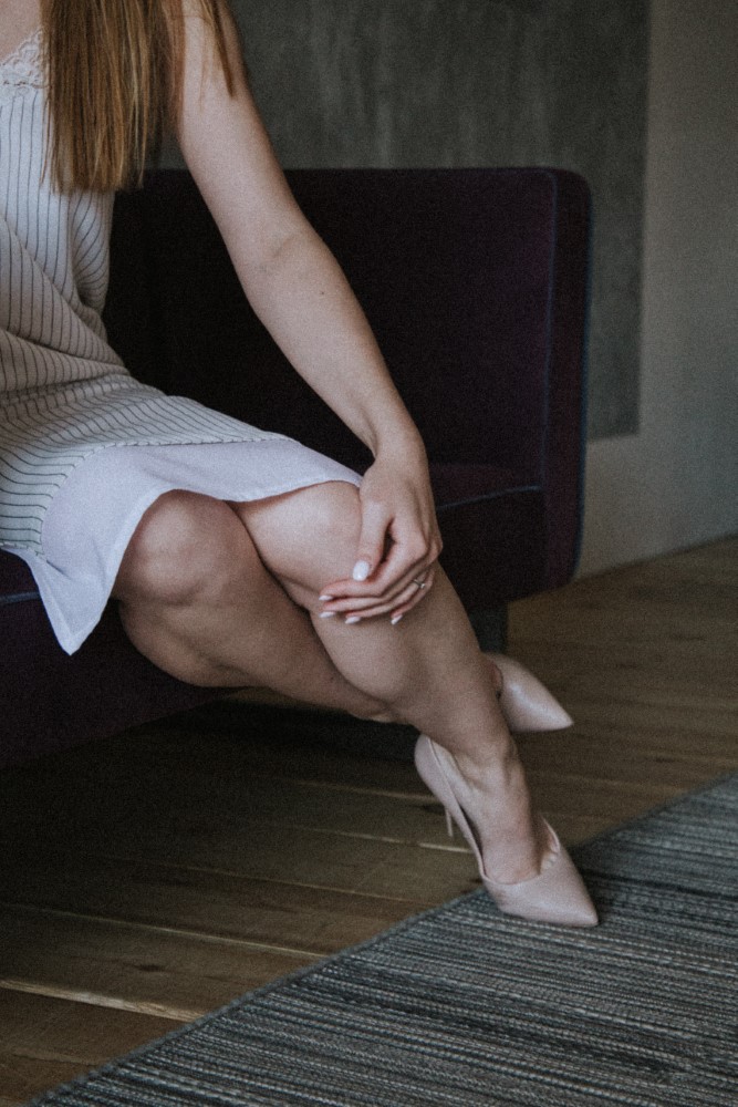 Mujer tocándose la pierna con dolor por rentención de líquidos Mujer tocándose la pierna con dolor por rentención de líquidos